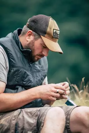Fly tying in a Filson ultralight vest and trucker cap