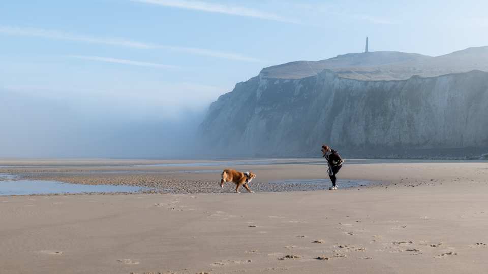 Richards and her dog Mimolette play together in front of Cap Blanc-Nez