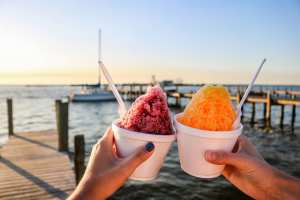 People holding up shaved ice on dock