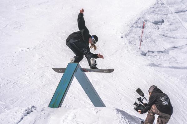 A snowboarder rides a rail in the park