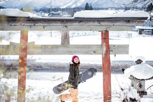 A snowboarder under a traditional Japanese archway