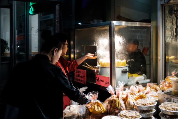 A street vendor selling corn on the cob, bread and cakes