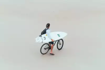 Man with surfboard on bike on Daytona Beach