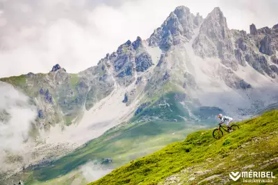 A lycra-clad cyclist hurtles down rough terrain in the Alps in Meribel