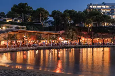 Evening lights glimmer along the Aegean beach