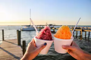 People holding up shaved ice on dock