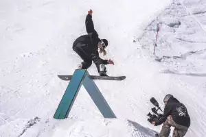 A snowboarder rides a rail in the park A snowboarder rides a rail in the park