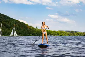 A woman paddleboards across Lake Baldeney A woman paddleboards across Lake Baldeney