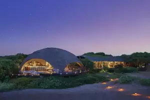 The open-air bar at Uga Chena Huts sits in front of a starry sky at dusk in Yala National Park – its thatched roof inspired by the treetop huts used by local farmers in the region
