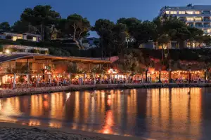 Evening lights glimmer along the Aegean beach