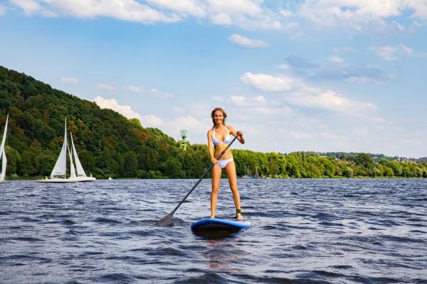 A woman paddleboards across Lake Baldeney A woman paddleboards across Lake Baldeney