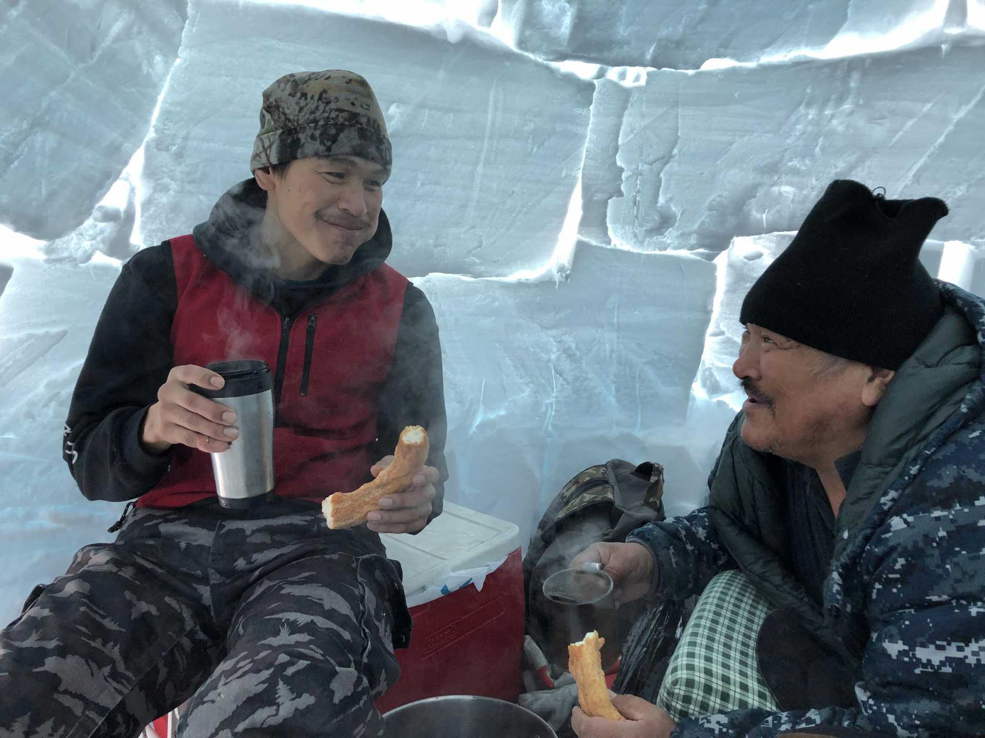Qalingo Sivurapak and Inukpak Itukallak enjoy bannock in an igloo in Nunavik