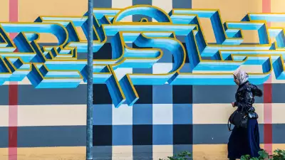 Woman walks in front of Bologna street art