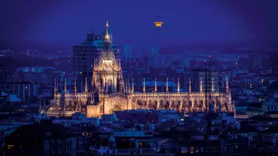 The duomo lit up at night in the skyline of Milan