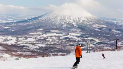 Snowboarder on slopes in Niseko, Japan, overlooking mountains