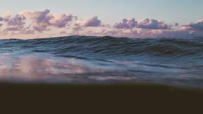 A rising wave with clouds reflected in the water