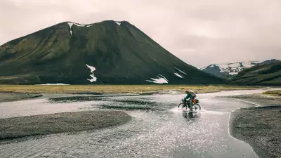 A bikepacker embraces soggy socks as he crosses a shallow river cycling the Kjolur Route in Iceland during the summer months
