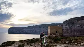 Biking-by-Xlendi-Tower,-Xlendi