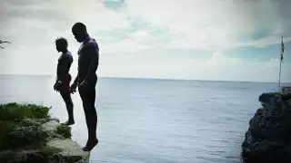 Two men prepare to dive from a cliff in Negril, Jamaica