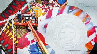 Two artists paint the Rose Kennedy Greenway mural from a cherry picker