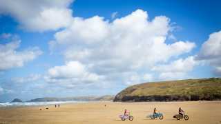 A family cycle the beach in Cornwall
