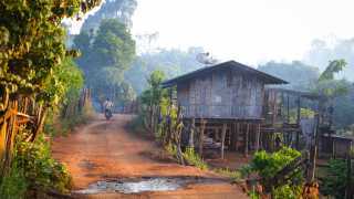 A motorcyclist drives through a tribal village