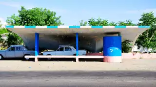 A bus stop with two cars underneath