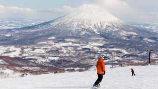 Snowboarder on slopes in Niseko, Japan, overlooking mountains