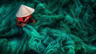 Vietnamese woman weaving a handmade fishing net