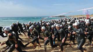 Swimmers enter the sea at the Chia Sardinia Triathlon