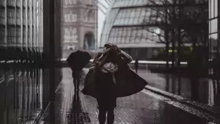 Woman sheltering under her coat in the City of London