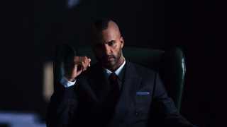 Ricky Whittle, star of American Gods poses in a suit and macintosh