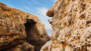 A young woman climbing the cliffs of Gozo, Malta