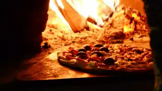 A pizza smouldering in a wood-fired oven