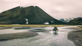 A bikepacker embraces soggy socks as he crosses a shallow river cycling the Kjolur Route in Iceland during the summer months