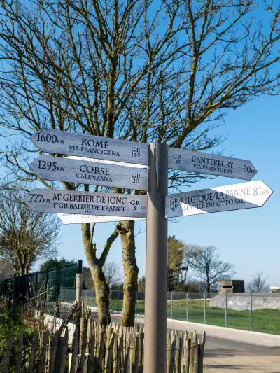 A white, wooden fingerpost marks different hiking trails in Calais
