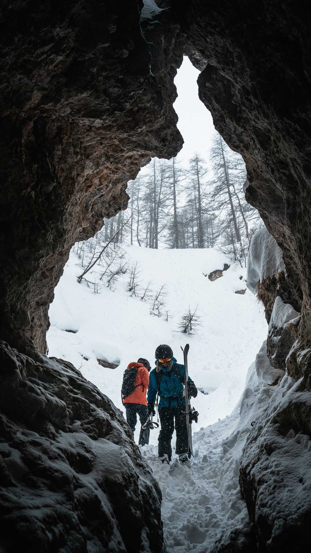 A skier walks through an opening in the mountain face in Val D'Isere