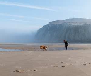 Richards and her dog Mimolette play together in front of Cap Blanc-Nez
