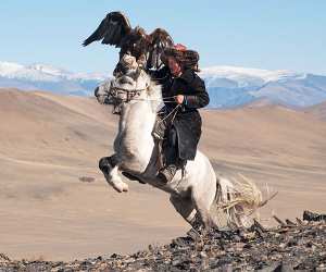 A mongolian hunter on horseback with an eagle