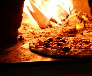 A pizza smouldering in a wood-fired oven
